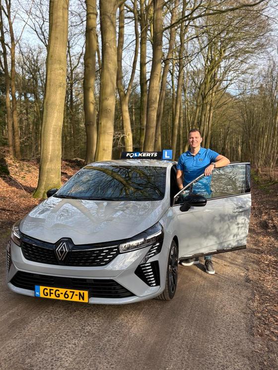 Niek Folkerts, rij-instructeur van Autorijschool Folkerts, bij de open deur van zijn lesauto
